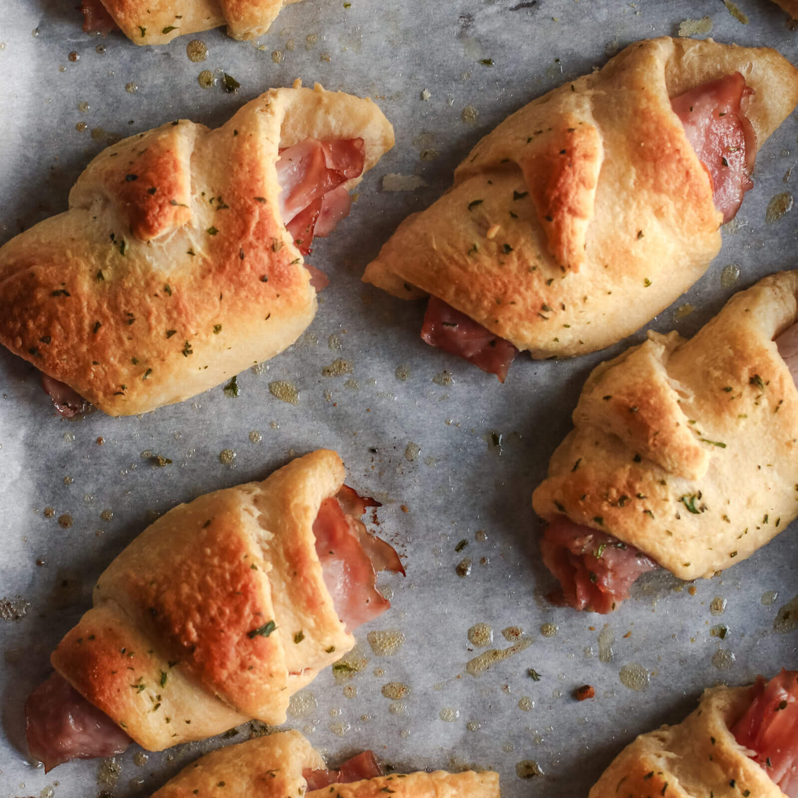 Ham and cheese crescent roll-ups on parchment paper