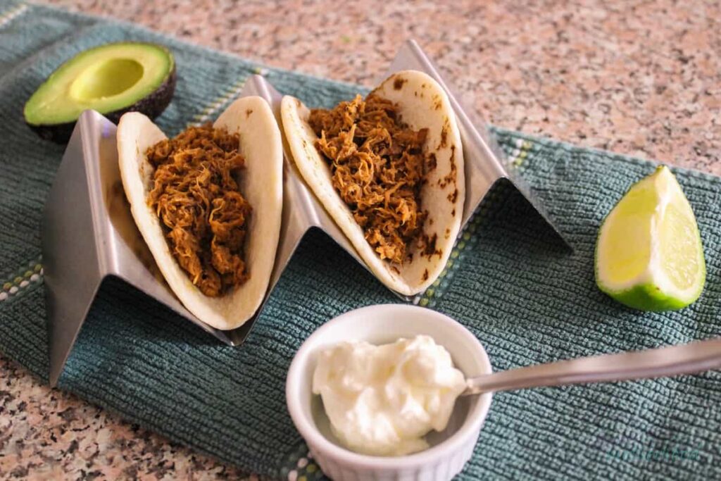 Pulled pork tacos, plus a lime, avocado half and ramekin of sour cream for photo decoration