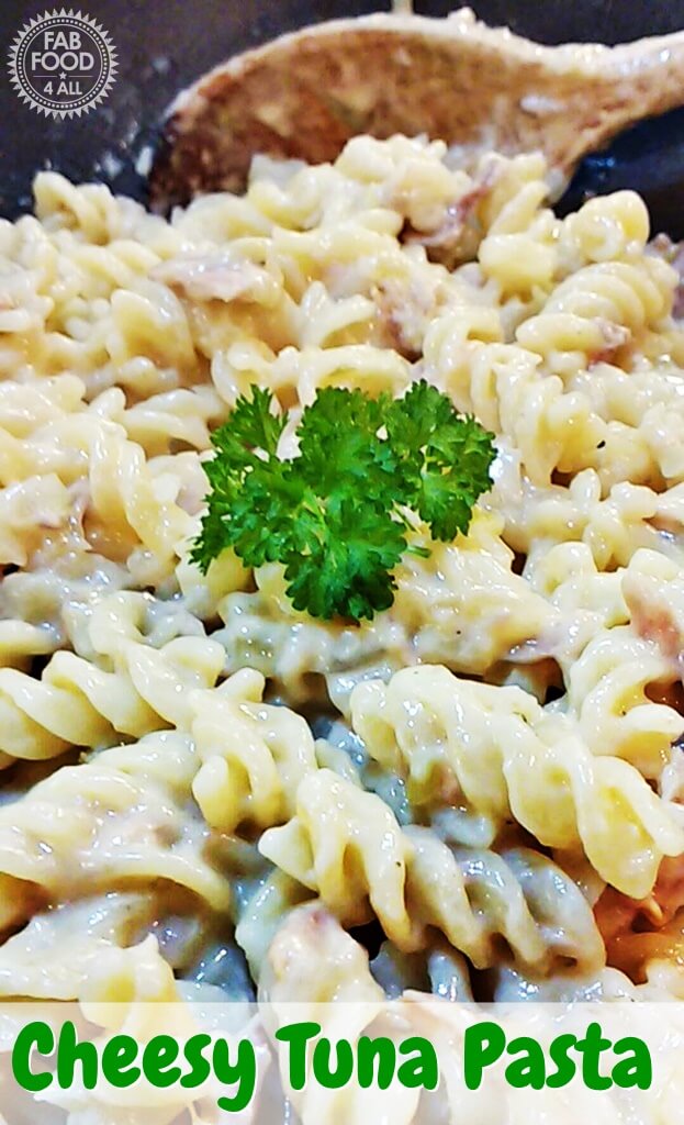 Cheesy tuna pasta with a garnish and wooden spoon in the background