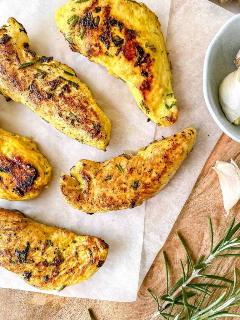 5 chicken fillets (cooked) colored yellow from turmeric, with pieces of rosemary